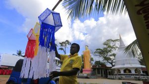 A Sri Lankan man hangs decorative lanterns outside a Buddhist Temple on the eve of Vesak, or Buddha Purnima, festival in Colombo