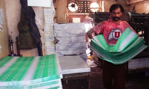 Labourer working at a printing press busy in printing national flags bunting on arrival of Pakistan Independence Day ahead on August 14, at Pakistan Chowk in Karachi