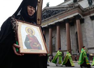 Russian Orthodox nun carries an icon during the Palm Sunday procession outside the Saint Isaac's Cathedral in Saint Petersburg, on April 9, 2017