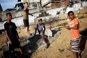 A boy (2nd L) flies his kite as his friends watch, in a cemetery in the Vila Operaria Favela of Rio de Janeiro, Brazil.