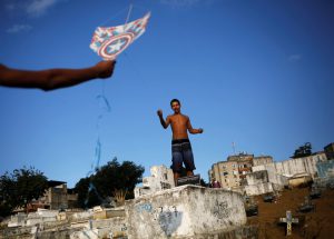 A man (L) helps his friend to fly a kite in a cemetery in the Vila Operaria Favela of Rio de Janeiro, Brazil.