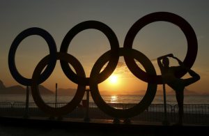 A girl is seen next to the Olympic rings as the sun rises over Fort Copacabana ahead of the Men's Road Race.