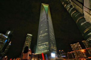 A woman takes photos of Shanghai World Financial Center (SWFC) as it is lit up in the colours of the Brazilian national flag for the Rio 2016 Olympics in the Pudongs Lujiazui Financial District in Shanghai on August 4, 2016.