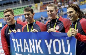 Nathan Adrian, Michael Phelps, Ryan Murphy, and Cody Miller hold a banner during the victory lap after winning gold in the Men’s 4 x 100-meter medley relay final during the swimming competitions at the 2016 Summer Olympics, August 14, 2016, in Rio de Janeiro, Brazil.