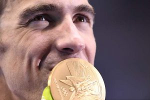 USA’s Michael Phelps kisses his gold medal on the podium after Team USA won the Men’s 4x200m Freestyle Relay Final during the swimming event at the Rio 2016 Olympic Games at the Olympic Aquatics Stadium in Rio de Janeiro on August 9, 2016.