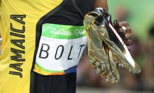 Usain Bolt carries his shoes in his hands after winning the gold medal.