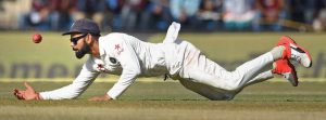 India’s Virat Kohli dives to stop the ball during the fourth day of third Test cricket match between the two teams at the Holkar Cricket Stadium in Indore on October 11, 2016.