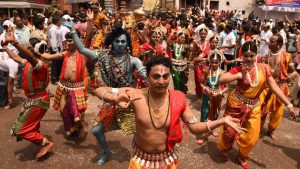 Odissi dancers and devotees in costumes depicting Hindu gods perform during the Rath Yatra festival in Puri