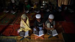 Saleema Khanam (L), studies inside a makeshift madrassa with other students in Kutupalong camp, near Cox's Bazar. She takes her position in the front, flanked by two brothers, and opens the book. “I come here to learn the Quran. My mother wants me and my brothers to learn, to become better people,” the young student told.