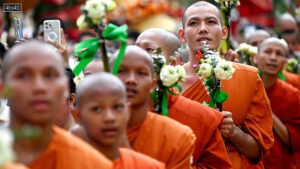 Buddhist monks hold lotus flowers as they pray during the Visak Bochea Buddhist celebration at a pagoda in Phnom Penh
